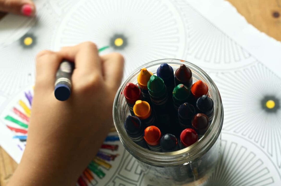 Dziecko koloruje kolorowankę kredkami